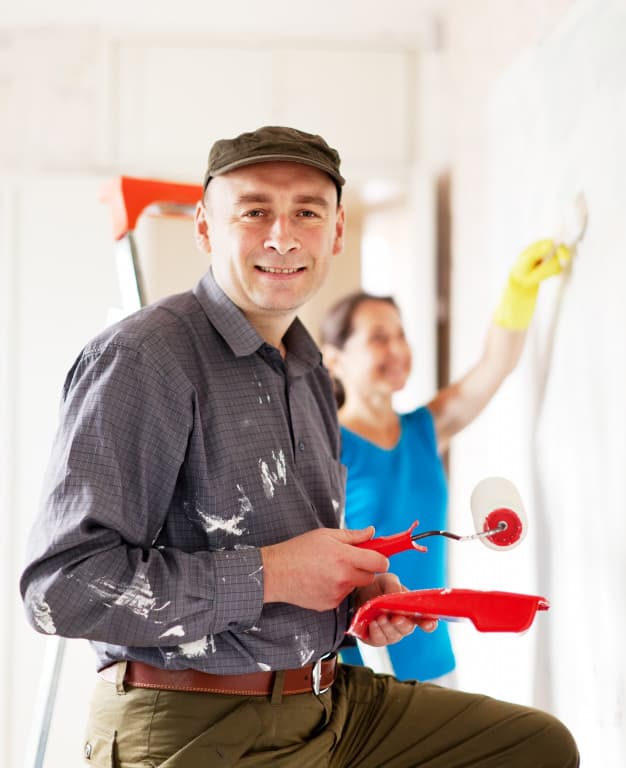 A room mid-repaint, two walls finished and the trim masked
